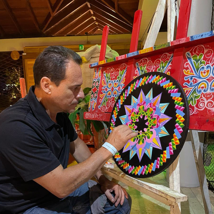 Artesano pintando a mano una tradicional rueda de carreta costarricense